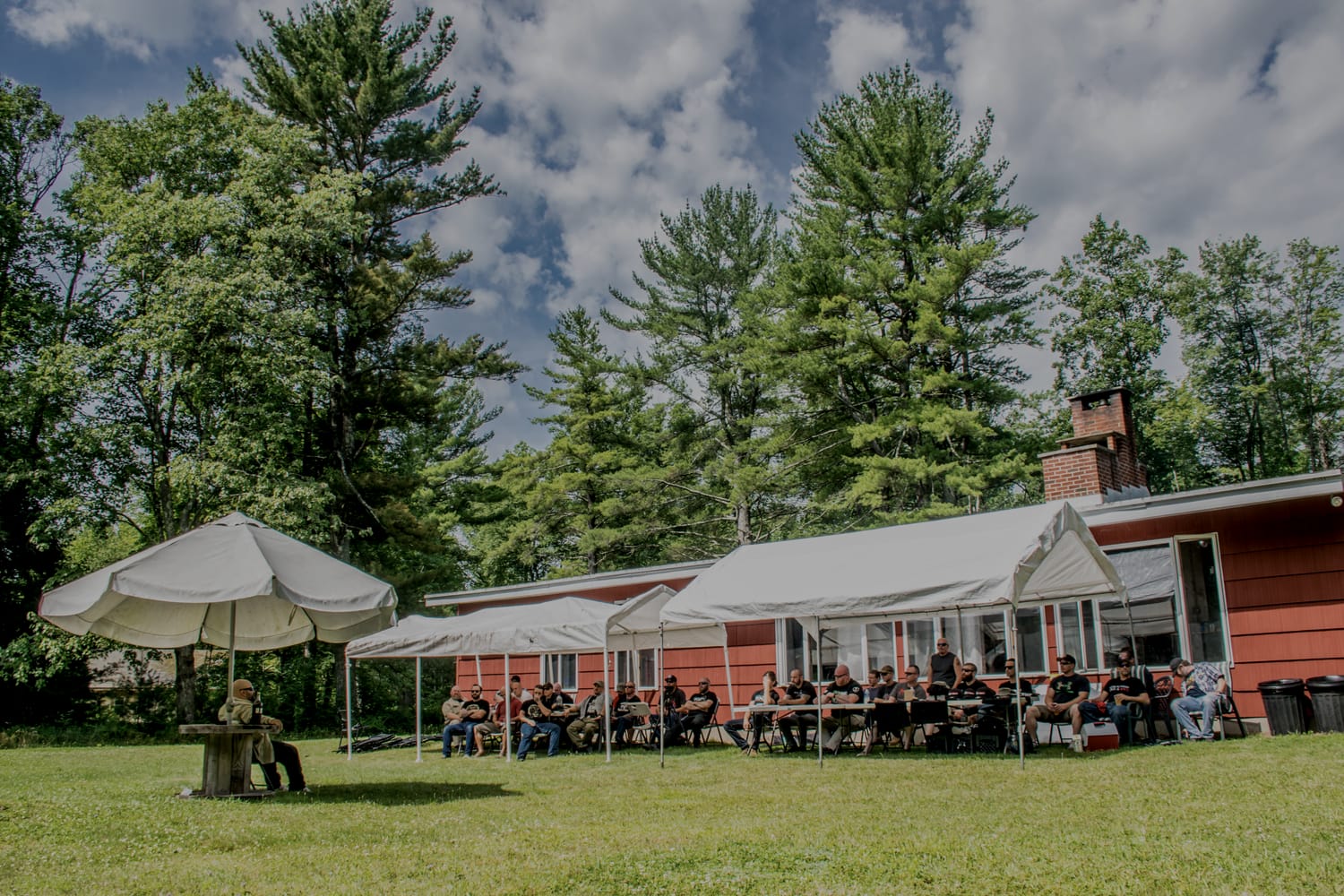 Attendees seated at tables by the secluded lodge in the Poconos at a prior PressureCon.